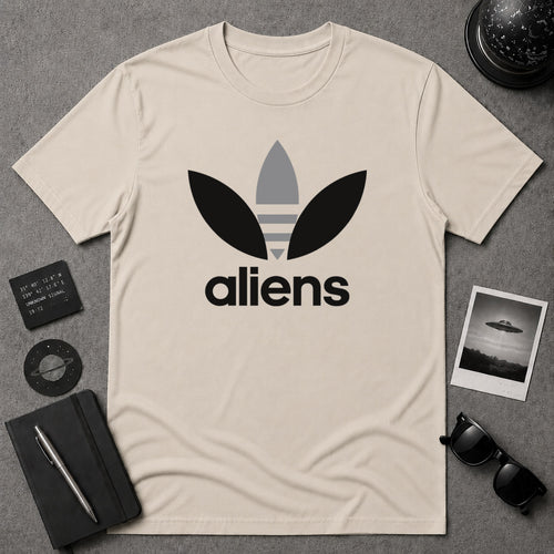 A beige graphic t-shirt featuring a black and gray alien-themed logo and the word 'aliens' printed on the front, visually reminiscent of the classic Adidas logo. This is a parody shirt.