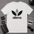 A white short-sleeve t-shirt with a black and gray alien-themed logo on the chest, visually reminiscent of the classic Adidas logo. This is a parody shirt.